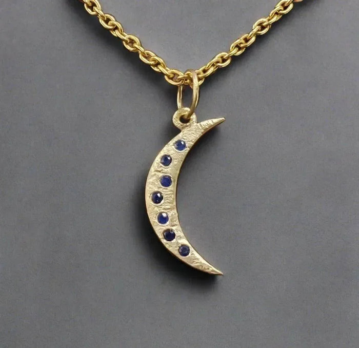 Gold crescent moon pendant with blue sapphire stones on chain, elegant jewelry accessory