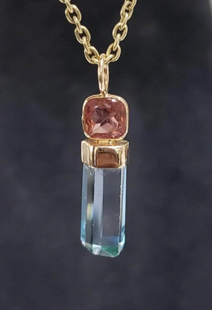 Gold pendant necklace with pink gemstone and blue crystal drop, elegant jewelry accessory