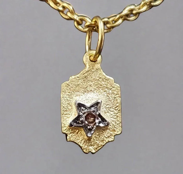 Gold pendant with star charm and diamond accent on textured tag, elegant jewelry accessory