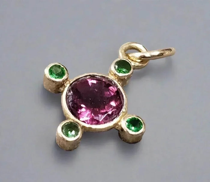 Gold pendant with pink tourmaline center and green emerald accents, elegant jewelry accessory