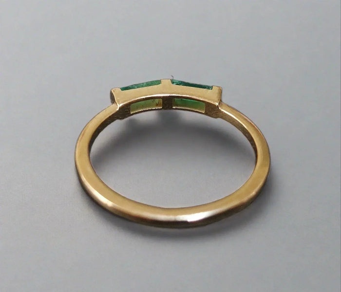Elegant gold ring with emerald green gemstones, showcasing sophistication and timeless design.