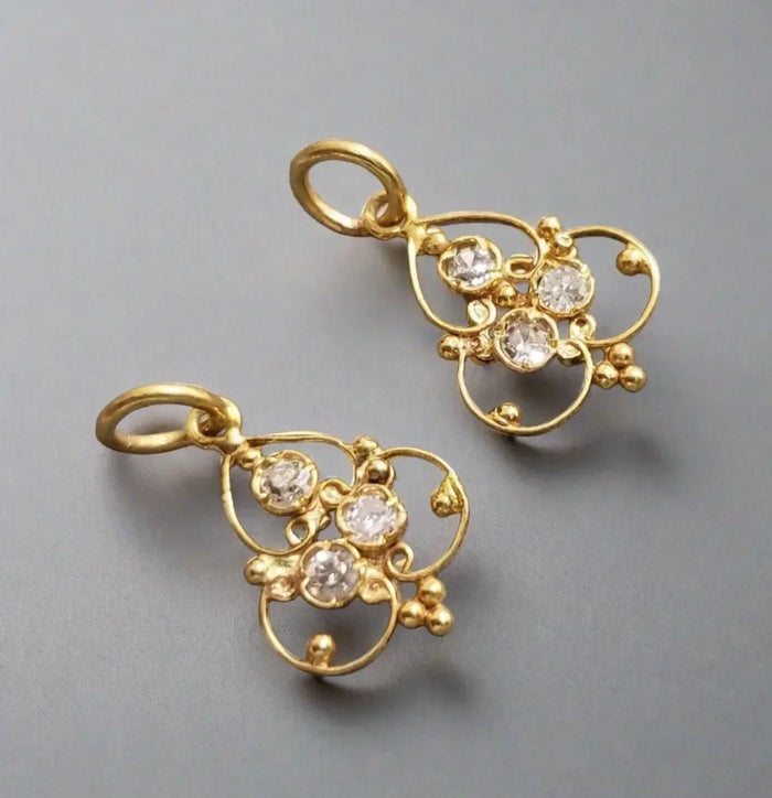 Elegant gold earrings with diamond accents, featuring intricate floral design and sparkling stones.