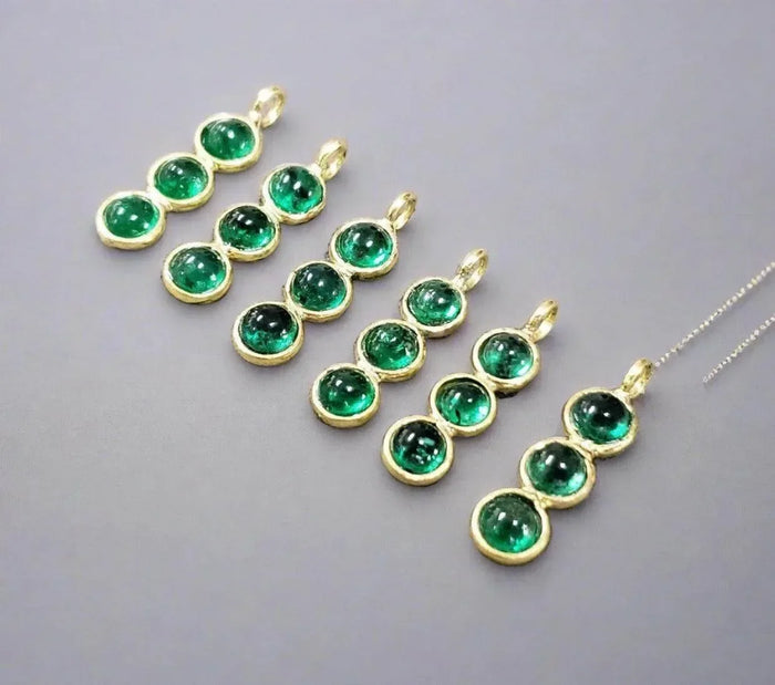 Elegant gold pendants with vibrant green gemstones, perfect for luxury jewelry collections