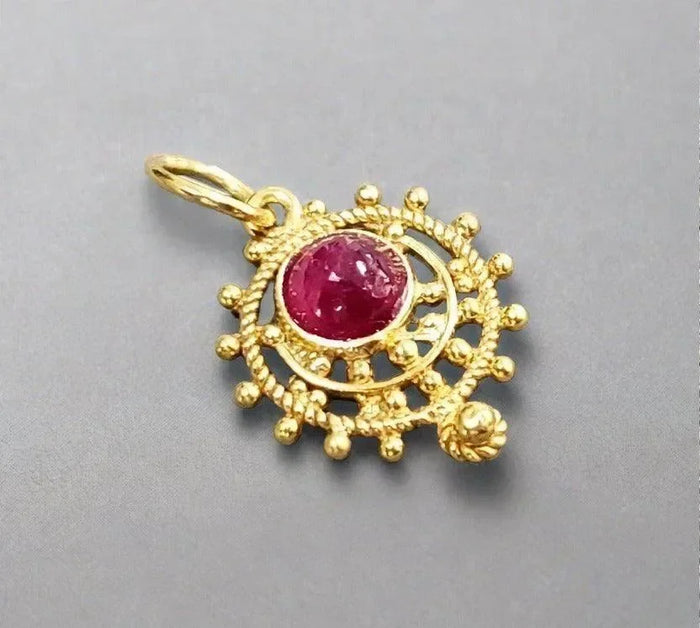 Elegant gold pendant with vibrant ruby gemstone, intricate filigree design, luxury jewelry accessory