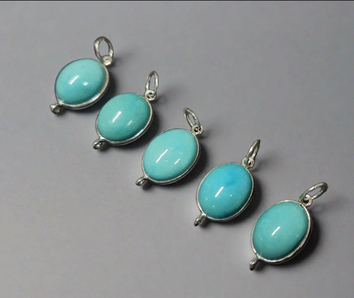 Five oval turquoise gemstone pendants in silver settings, elegant jewelry accessories