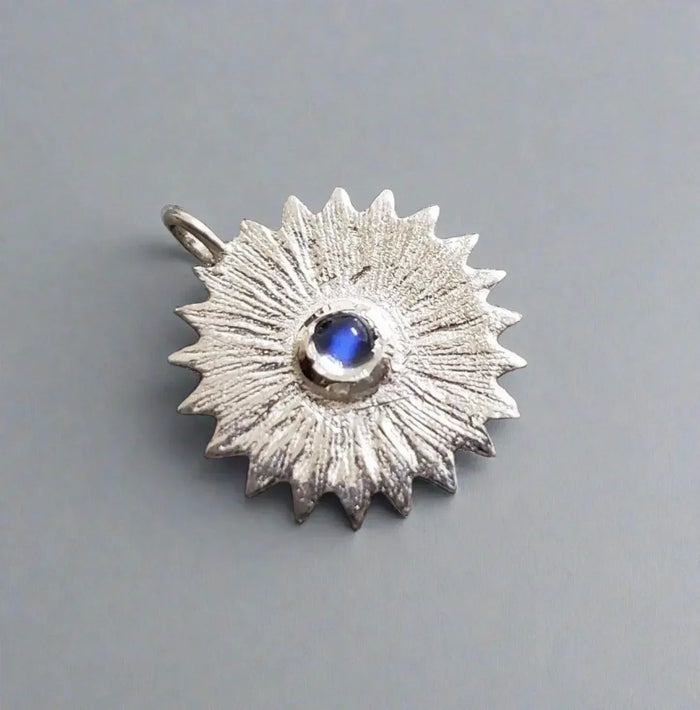 Silver sunburst pendant with blue gemstone, elegant jewelry accessory