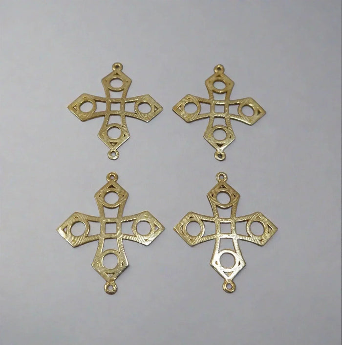 Four gold cross pendants with intricate cutout designs, ideal for elegant jewelry making