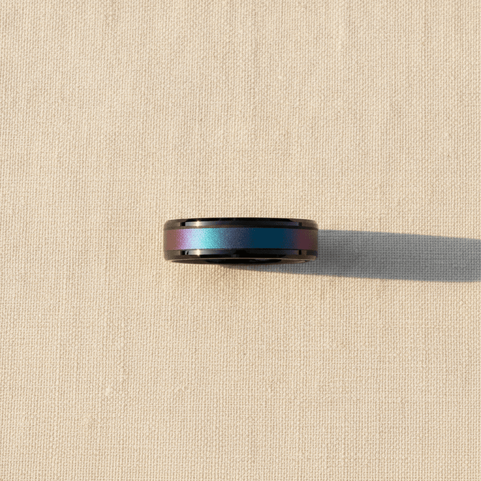 BARRACUDA black ceramic ring with purple to teal color-shifting inlay macro detail overhead flat lay