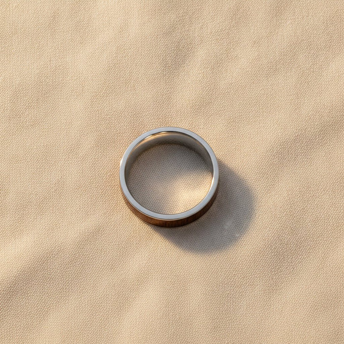 BOKKEN flat silver tungsten wedding band with black walnut wood inlay running around the band and polished silver edges macro detail overhead flat lay