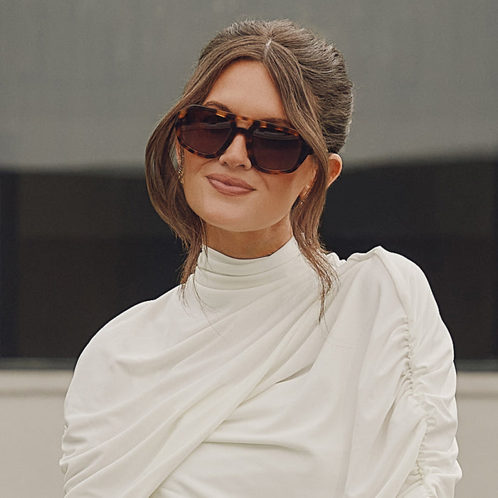 lifestyle - caitlin covington looking at the camera wearing diff eyewear featuring the collins navigator sunglasses with a spotted tortoise acetate frame and brown gradient polarized lenses