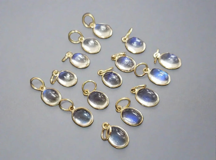 Elegant gold charms with oval moonstone gems, perfect for luxury jewelry designs