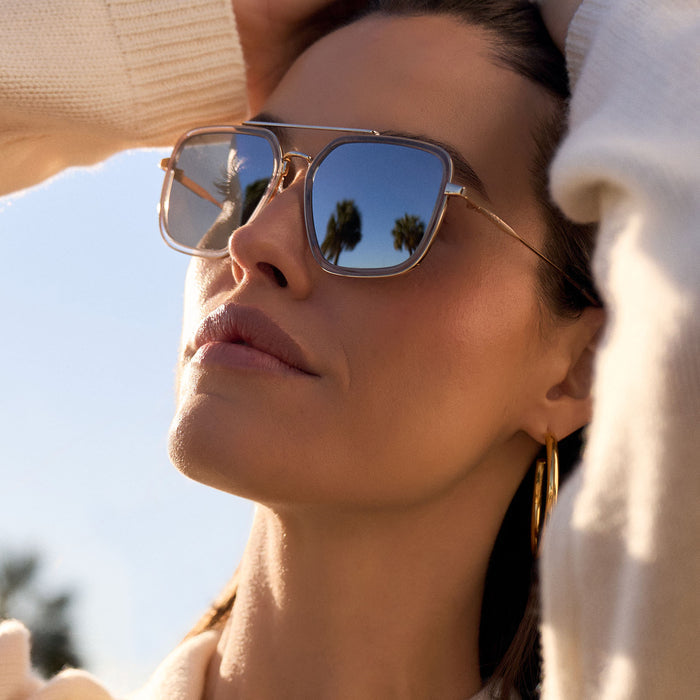 lifestyle - female wearing diff eyewear featuring the jordan navigator sunglasses with a gold frame, clear crystal temple tips and silver mirror lenses angled view
