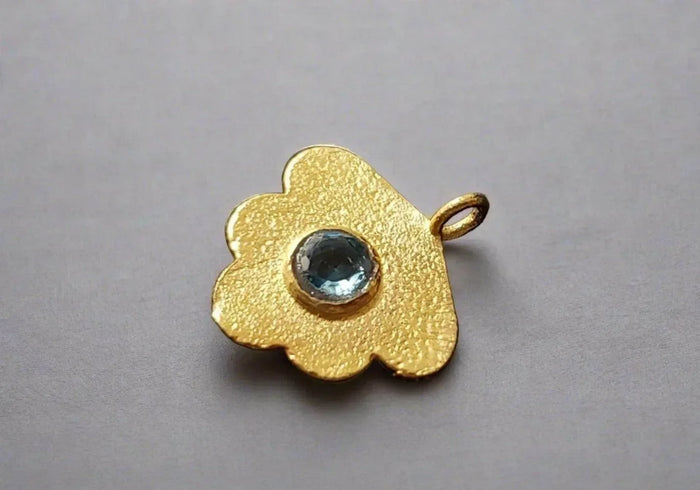 Gold flower pendant with blue gemstone, elegant jewelry accessory