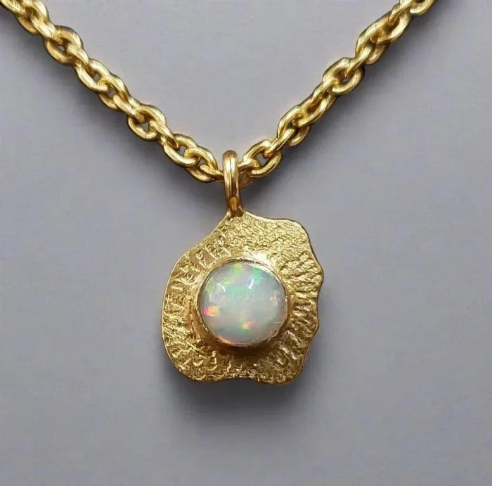 Gold necklace with textured pendant featuring a white opal gemstone, elegant jewelry accessory