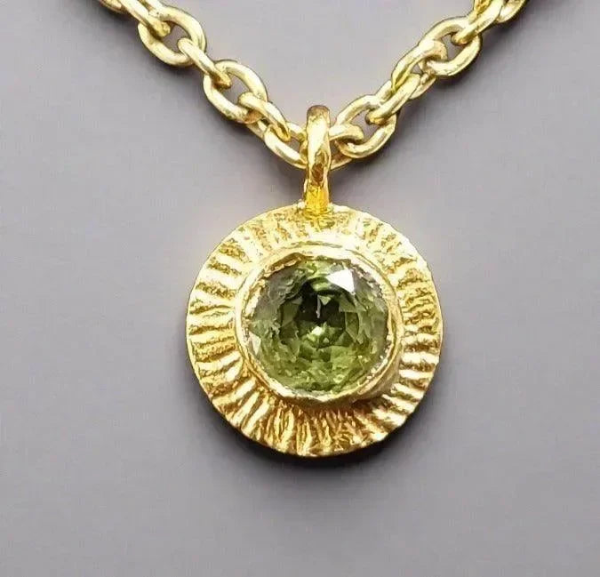 Gold pendant necklace with textured bezel and green gemstone, elegant jewelry accessory