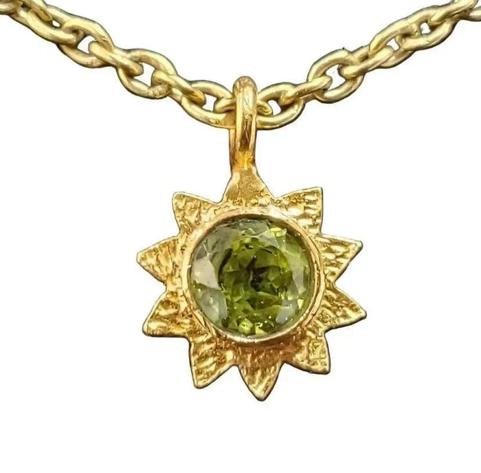 Gold sunburst pendant necklace with green gemstone, elegant jewelry accessory