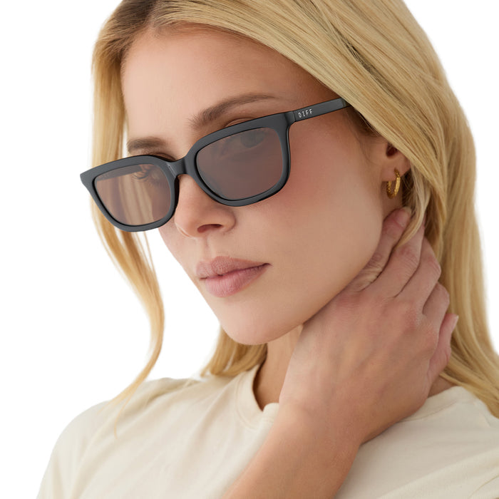 on model - female wearing diff eyewear hannah square sunglasses with a black acetate frame and brown polarized lenses angled view