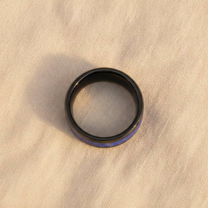 MARLOW polished black ceramic wedding band with blue lapis stone inlay running around the band and polished beveled edges macro detail overhead flat lay