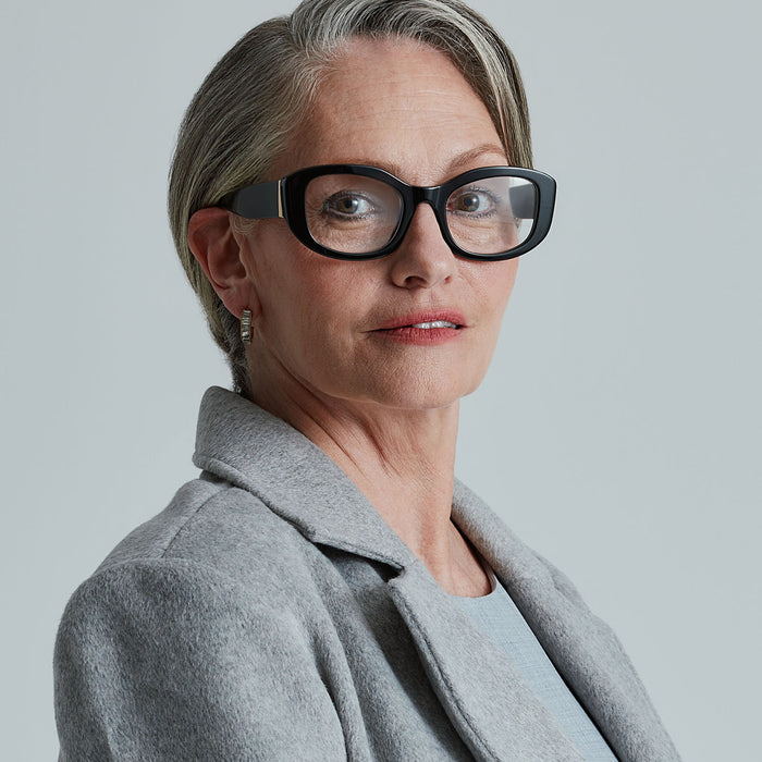 lifestyle - business suited female wearing the devil wears prada x diff eyewear featuring the miranda square oversized prescription glasses with a black acetate frame angled view