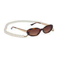 caitlin covington x diff eyewear featuring the nancy round sunglasses with a spotted tortoise frame and brown gradient polarized lenses angled view with chain