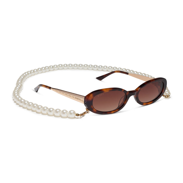 caitlin covington x diff eyewear featuring the nancy round sunglasses with a spotted tortoise frame and brown gradient polarized lenses angled view with chain