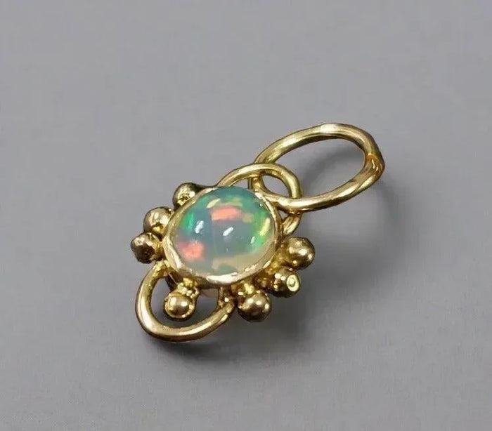 Elegant gold pendant with vibrant opal gemstone, showcasing luxury jewelry design