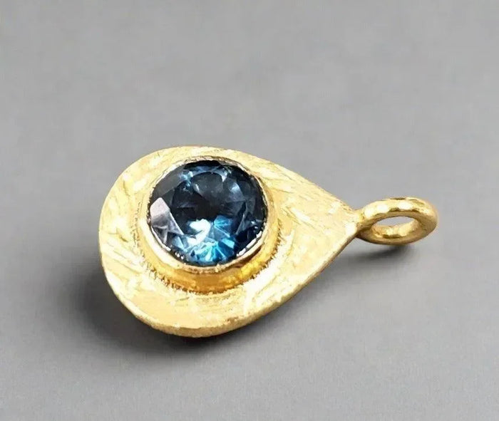 Gold teardrop pendant with blue gemstone, elegant jewelry accessory