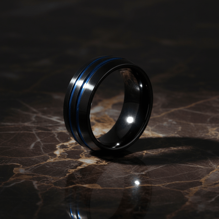 PETROS — Luxury 3/4 angle on dark marble — men's tungsten wedding ring.