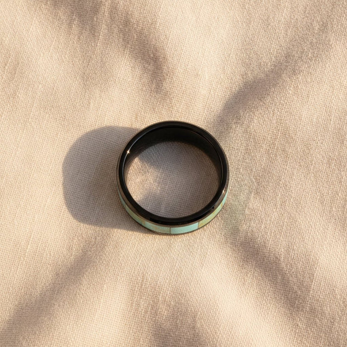 PIETRO polished black ceramic wedding band with light blue turquoise stone inlay running around the band and polished beveled edges macro detail overhead flat lay