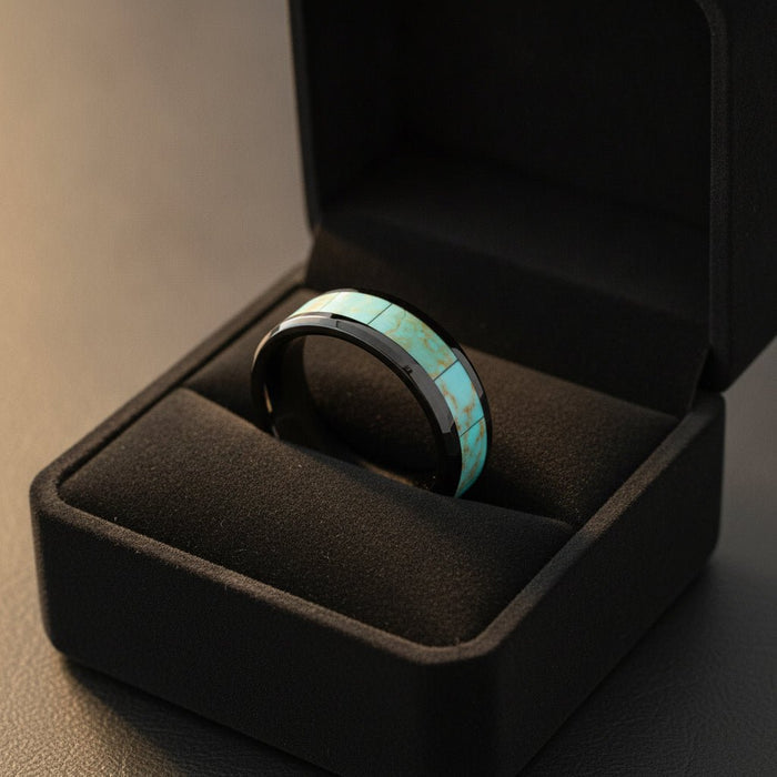 PIETRO polished black ceramic wedding band with light blue turquoise stone inlay running around the band and polished beveled edges nested in a black velvet ring box, editorial jewelry shot