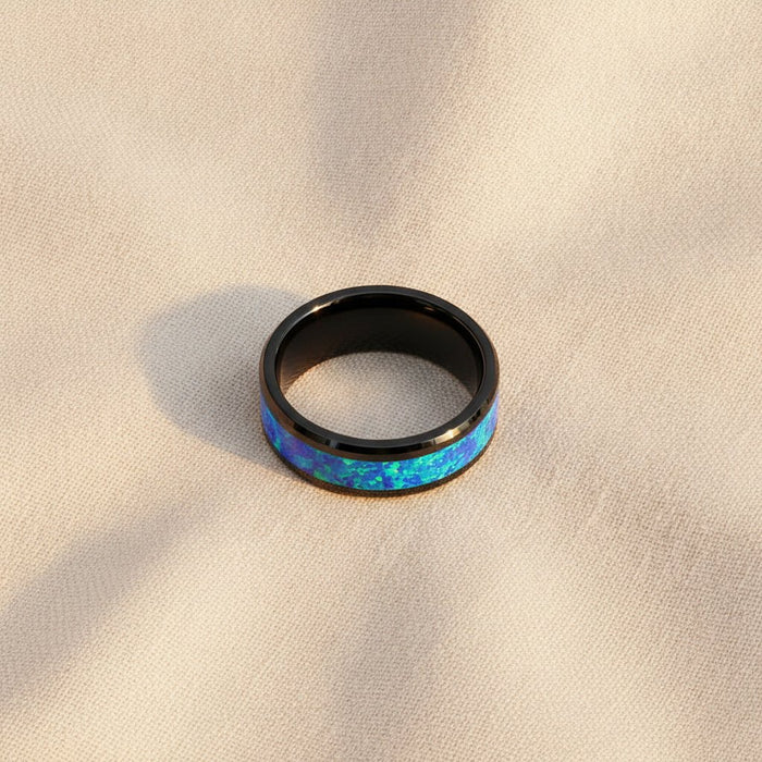 QUANTUM black ceramic wedding band with blue and green opal inlay running around the band and polished beveled edges macro detail overhead flat lay