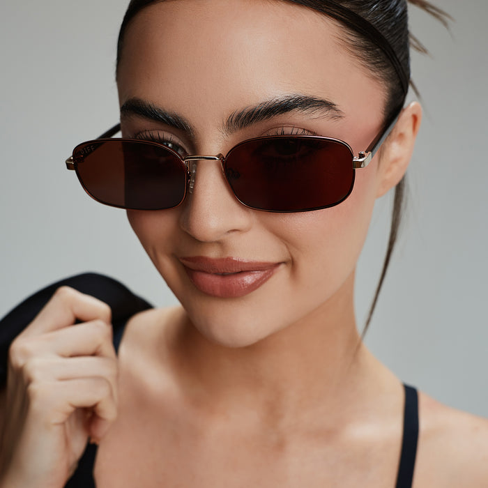 lifestyle - rachael kirkconnell wearing diff eyewear naomi square sunglasses with a brown and gold metal frame and brown lenses front view