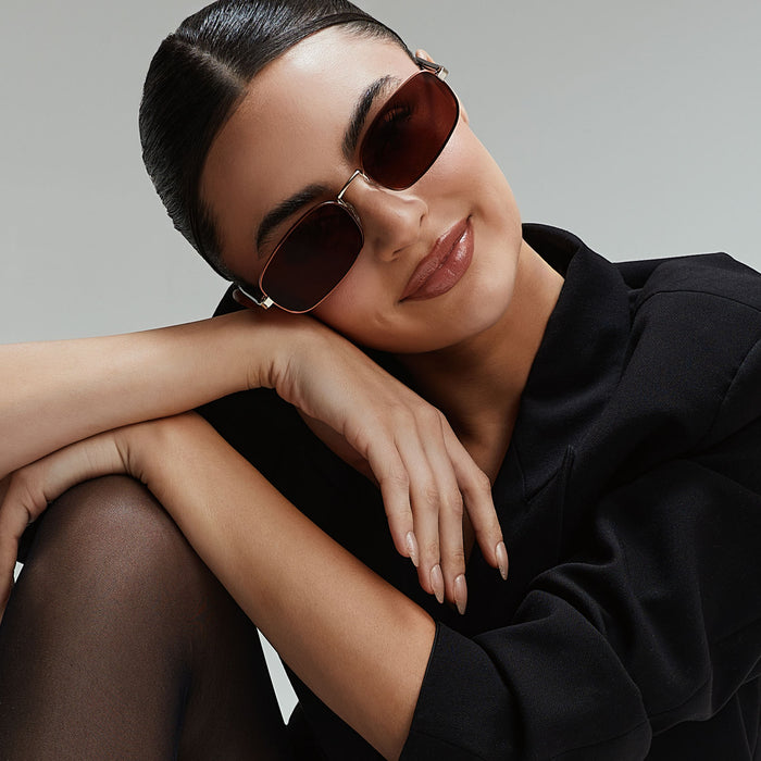 lifestyle - rachael kirkconnell wearing diff eyewear naomi square sunglasses with a brown and gold metal frame and brown lenses angled view