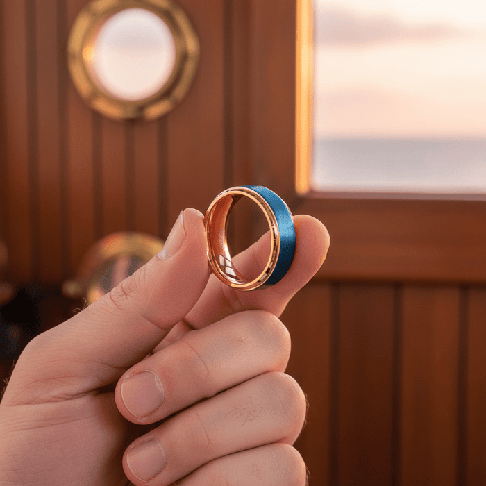 ZION — Held between fingers close-up — men's tungsten wedding ring.